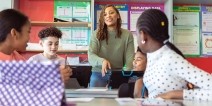 A teacher answering questions in front of a classroom of students.