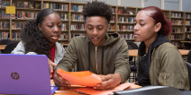Three high school students working on a project in a school library.