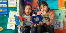 Two elementary girls reading Spanish language books.
