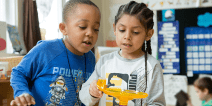 Two elementary students using a marble activity maze.