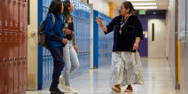 Students and teacher talking together in a hallway with lockers