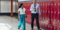 A teacher and a principal talking while walking in a school hallway.