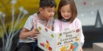 Two elementary students reading a book together.