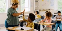 A teacher giving a student a high five in a classroom.