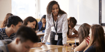 A teacher talking to a group of students in a classroom.