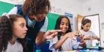 A teacher helping students finger paint.