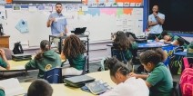A teacher presenting a lesson while a student teacher watches.