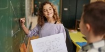 Two students solving a math equation on a blackboard.