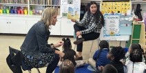 Two teachers reading a book to a group of kindergarteners.