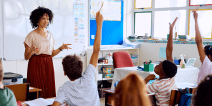 Elementary school teacher asking question, enthusiastic children with hands up
