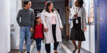 An educator talking with a family in a school hallway.