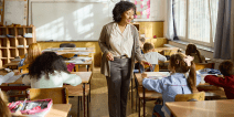 A teacher assists an elementary student in a classroom.