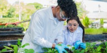 Two high school students wearing lab coats in a plant nursery.
