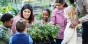 diverse students gather around a teacher leading them in a gardening activity