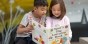 Two elementary students reading a book together.