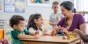 A teacher assisting preschool students in a classroom.