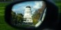 A photo of the California State Capitol building in the sideview mirror of a car.