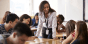 A teacher talking to a group of students in a classroom.