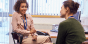 Two women having a discussion at a table.