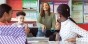 A teacher answering questions in front of a classroom of students.