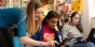 A teacher helping a student on a laptop.