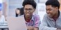Two high school students working together on a laptop.