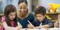 A teacher assists preschool students with a task.