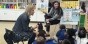 Two teachers reading a book to a group of kindergarteners.